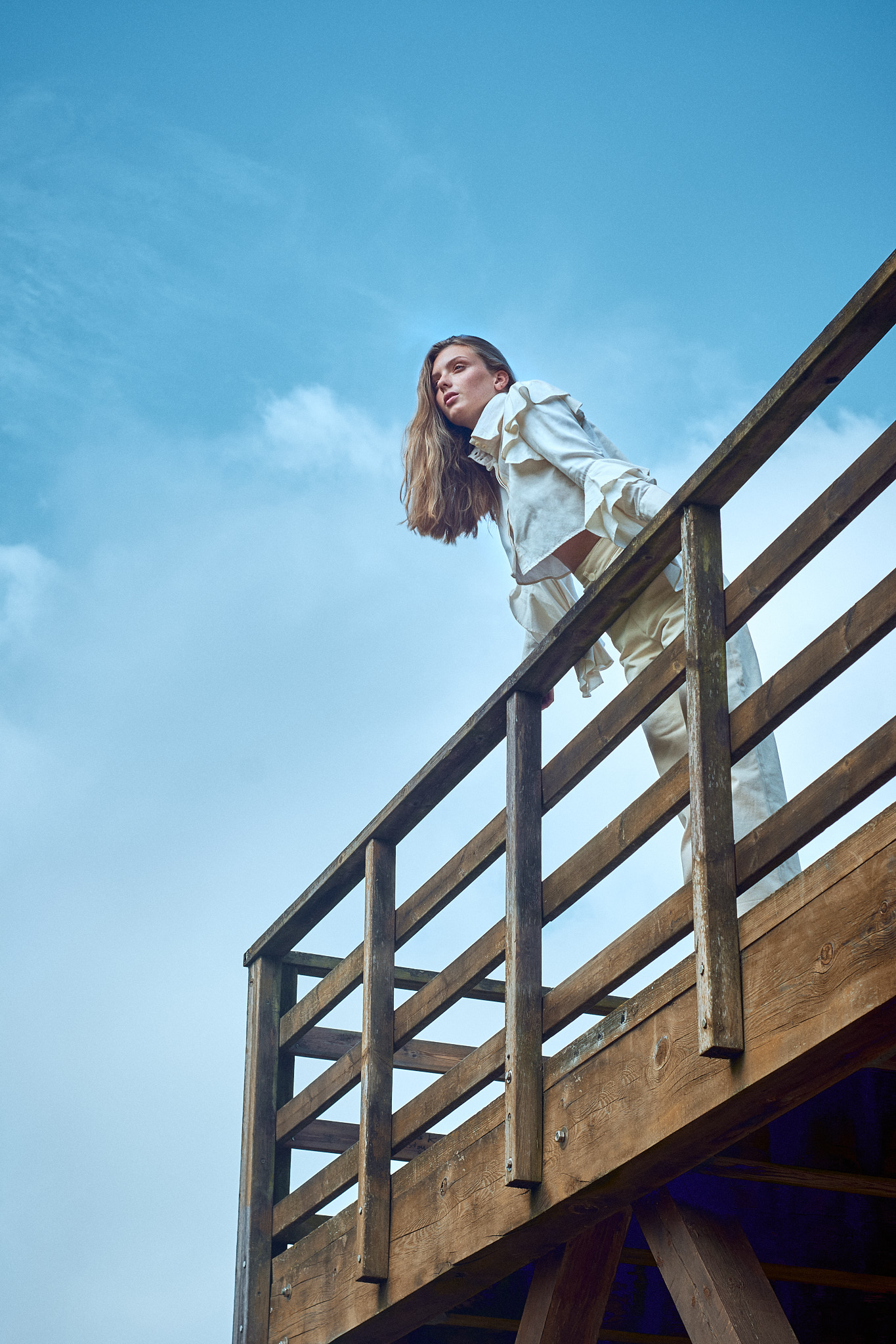 fashion editorial portrait model standing on wooden bridge countryside