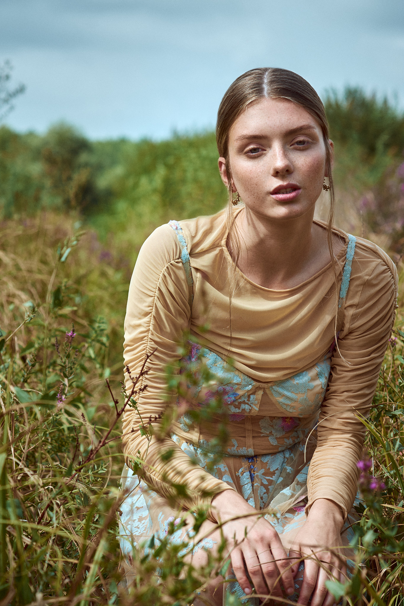 fashion editorial portrait model sitting in countryside field