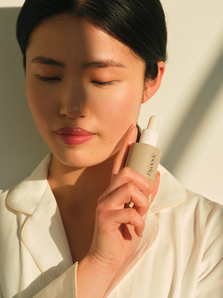 Beauty portrait applying Byoode skincare serum — campaign produced for Moodka